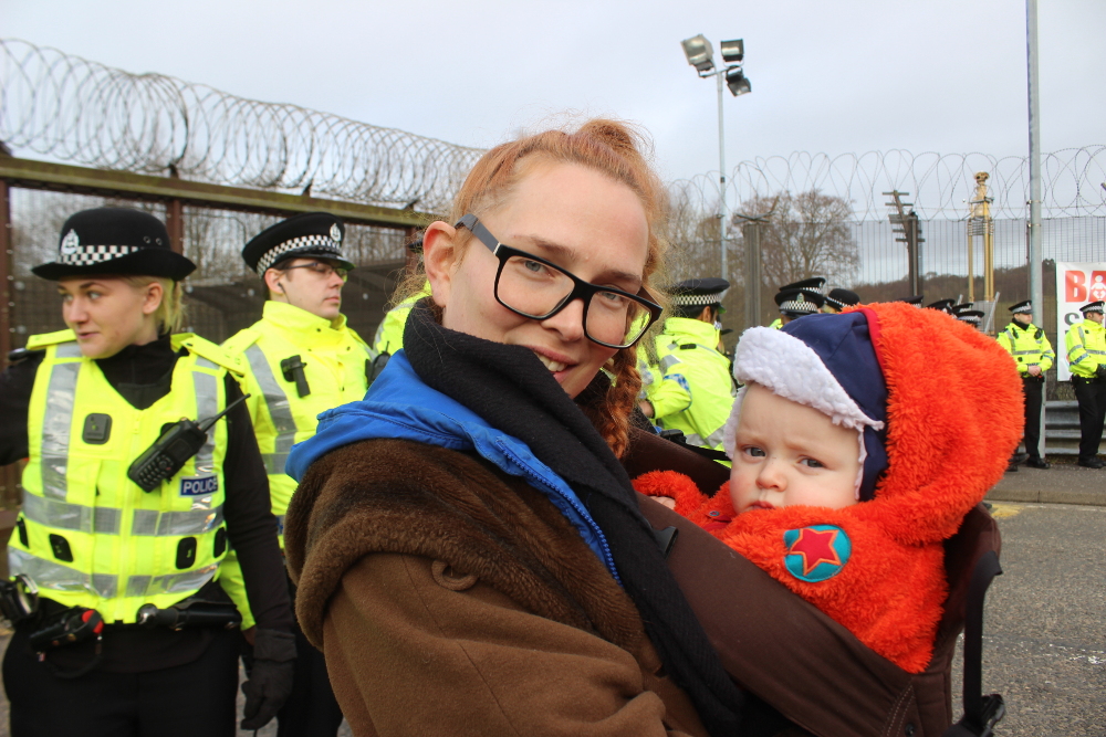 Mother and baby in front of police line.