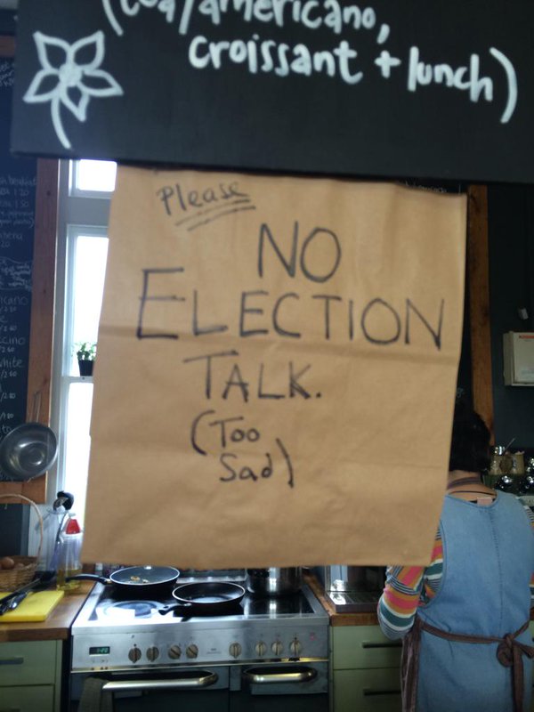 A handwritten sign with the words "Please no election talk. (Too sad)" hanging below a cafe menu