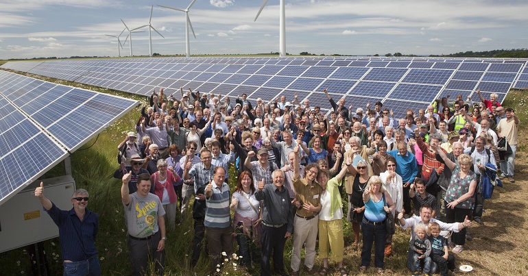 Crowd of people in front of wind turbines and solar panels