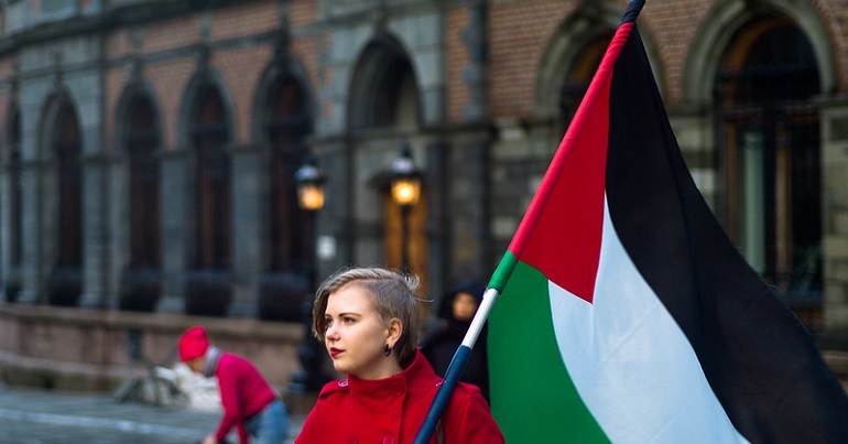 Young woman carrying a Palestinian flag