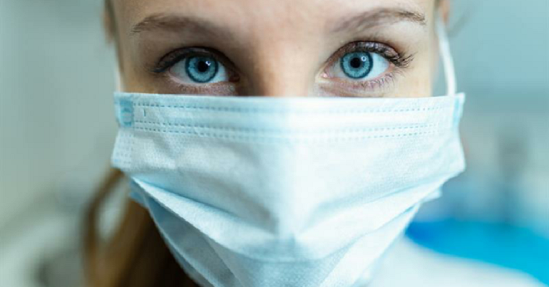 A face with eyes visible and mouth and nose covered by PPE