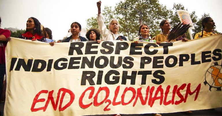 A protest with a banner reading "Respect indigenous peoples rights: End co2lonialism.