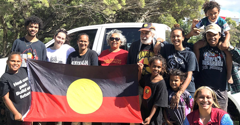 A group of people holding an Australian First Nations flag