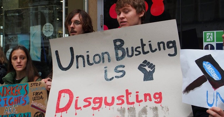A group of anti-sweatshop protesters with a sign reading "union busting is disgusting"