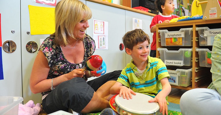 A staff member in children's services playing music with a child