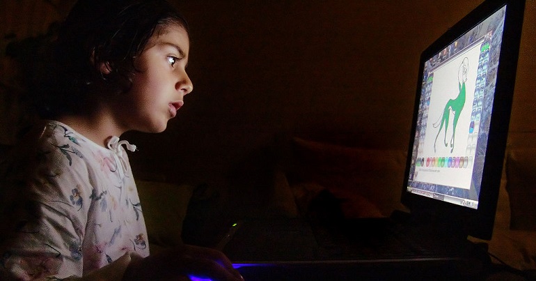 A child using a computer in the dark