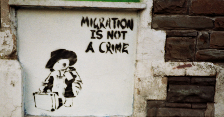 A photo of stencil graffiti which shows an image of Paddington Bear with text reading "Migration is not a crime"