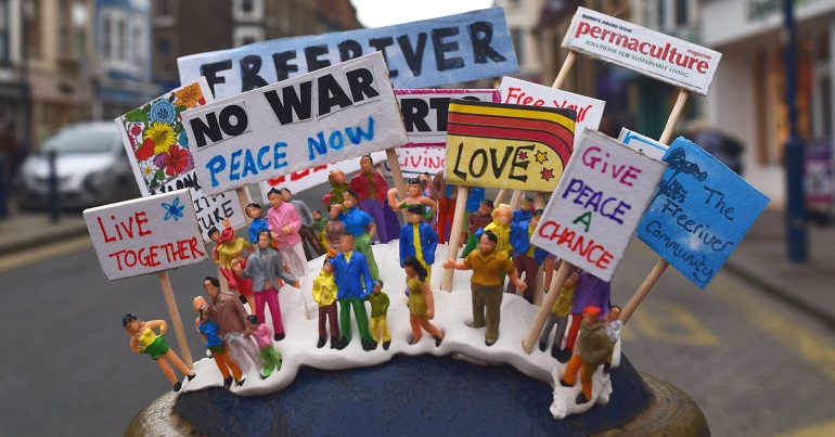 A photo of an artwork of people holding placards with peace slogans