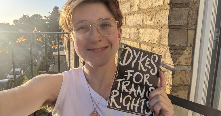A photo of Lucy Pegg holding a sign which reads "Dykes for trans rights"