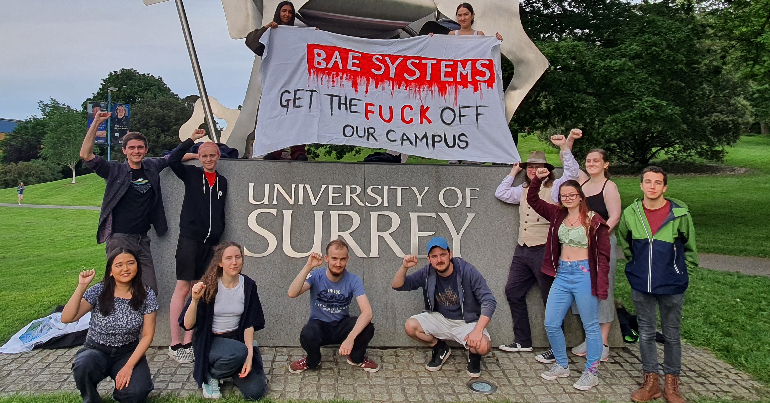 A photo of student campaigners at the University of Surrey holding a banner reading "BAE Systems: Get the fuck off our campus"