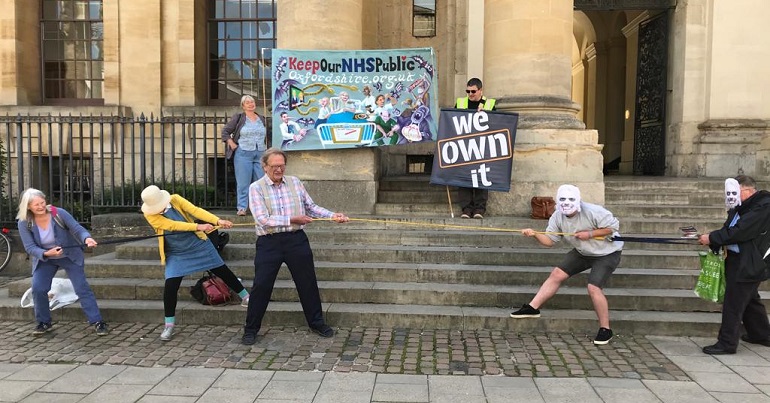 A photo of NHS campaigners in Oxford staging a tug of war between Richard Branson and the public. 