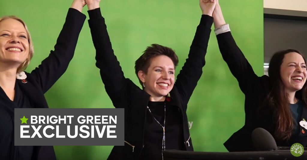A photo of Green Party figures Sian Berry, Carla Denyer and Amelia Womack raising their hands aloft
