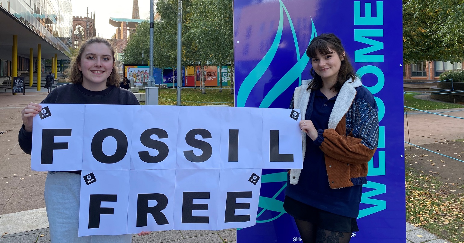 Two student campaigners at Coventry University holding a banner reading 'fossil free'
