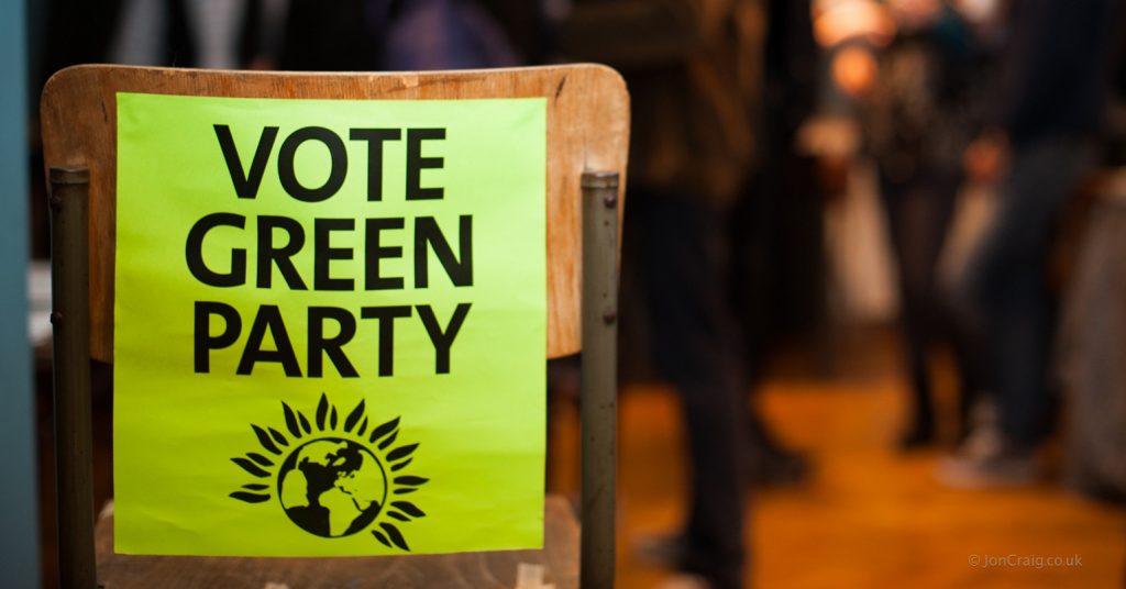 A poster reading "Vote Green Party" on the back of a chair