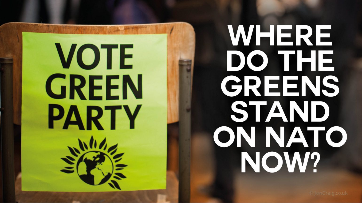 A photo of a poster on the back of a chair reading "Vote Green Party". There is text overlaid reading "Where do the Greens stand on NATO now?"