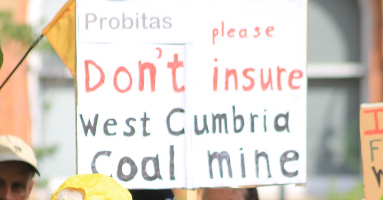 A placard reading "don't insulate West Cumbria coal mine"