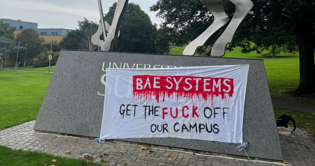 A banner dropped by student activists at the University of Surrey reading "BAE systems: Get the fuck off our campus"